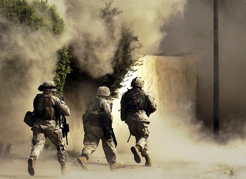 Three soliders run toward the smoke from an explosion, guns ready.