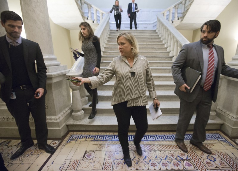Landrieu descends a marble staircase surrounded by political aides.