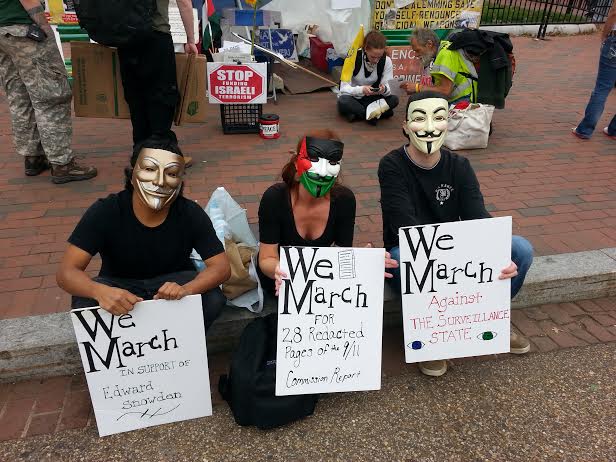 Masked activists signs explain their issues.