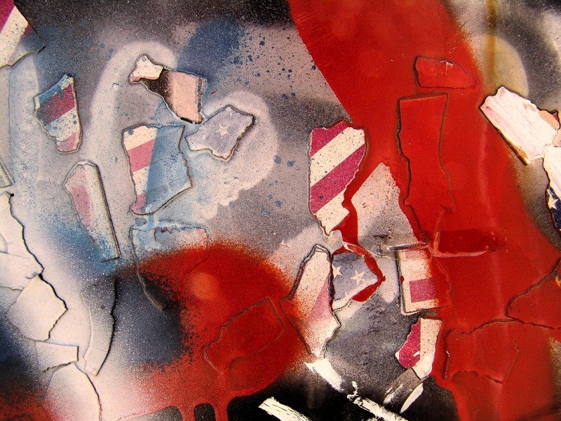 Broken up fragments of the American flag, coated in red paint.