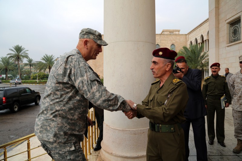 The two army leaders exchange a handshake in front of a pillar, outside their meeting place.