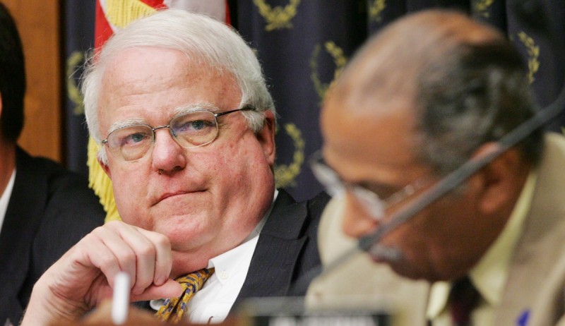 Sensenbrenner is wearing a suit and frowning, sitting next to another representative who is studying something out of frame.
