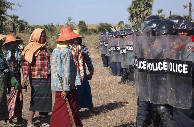 Farmers with sticks confront riot cops in full armor with shields.