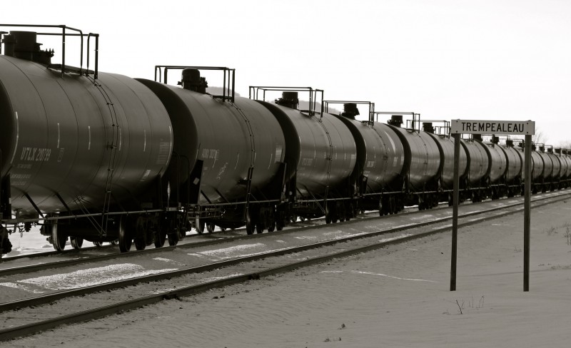 An endless row of oil tank cars one after another as a massive oil train passes the camera.