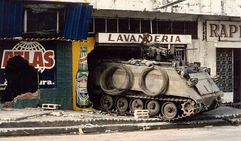 An armored vehicle stands guard in the rubble of a laundromat, near other destroyed civilian shops. 