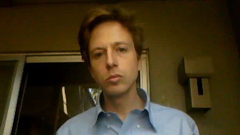Barrett Brown, pictured looking into a webcam while wearing a blue dress shirt, was facing a slew of charges. On January 22, 2014 he was sentenced to an additional 35 months in prison. (Photo/screen grab via YouTube)