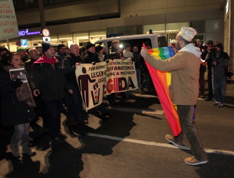 A counter demonstrator with a rainbow peace flag opposes the demonstration of Legida, an offshoot of the Pegida anti-Islam movement, in Leipzig, eastern Germany, Wednesday, Jan.21, 2015. (AP Photo/dpa, Sebastian Willnow)