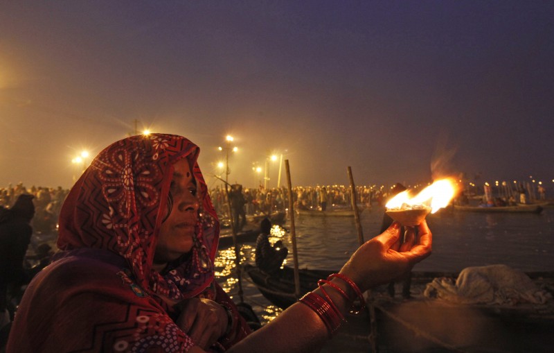 A Hindu woman devotee holds an oil lamp and offers prayers to the Sun god after taking a holy dip at the Sangam, the confluence of the Ganges and Yamuna rivers, on "Mauni Amavasya" or new moon day, the third and most auspicious date of bathing during the annual month long Hindu religious fair "Magh Mela" in Allahabad, India,Tuesday, Jan. 20, 2015. Hundreds of thousands of Hindu pilgrims take dips in the confluence, hoping to wash away sins during the month long festival. (AP Photo/ Rajesh Kumar Singh)
