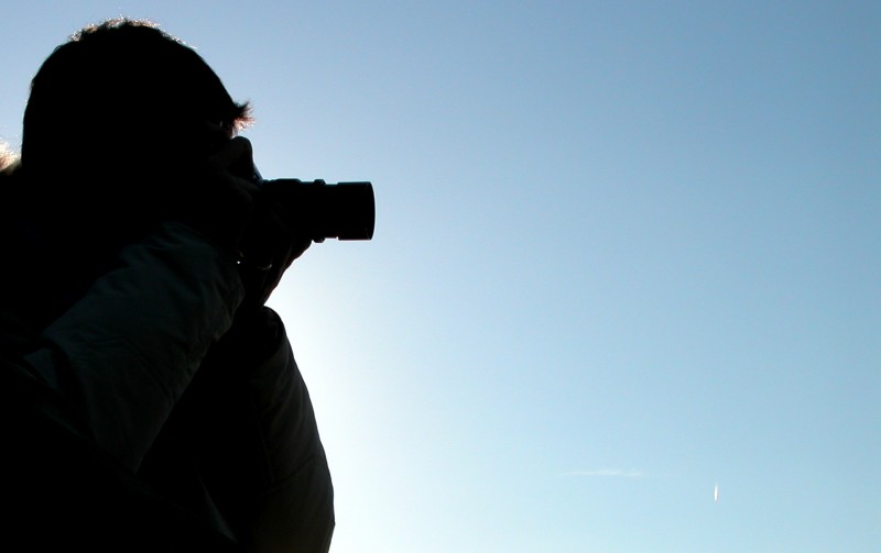 File: Silhouetted against a blue sky, a photograher takes aim.