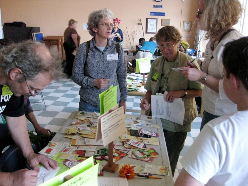 Library patrons surround tables covered in seed packets.
