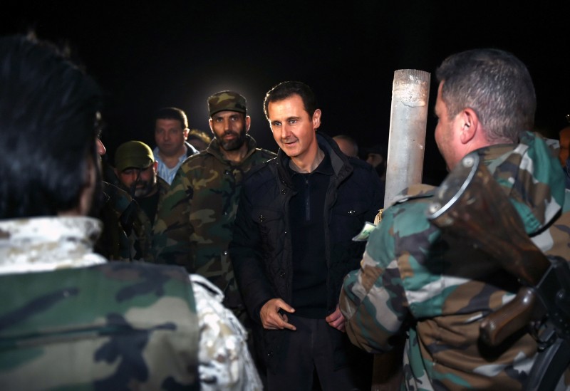 In this Wednesday, Dec. 31, 2014 photo released by the Syrian official news agency SANA, Syrian President Bashar Assad, center, speaks with Syrian troops during his visit on the front line in the eastern Damascus district of Jobar, Syria. Assad has made a rare visit to the front line of his country's civil war, spending New Year's Eve with his troops in a tense eastern Damascus neighborhood. (AP Photo/SANA)