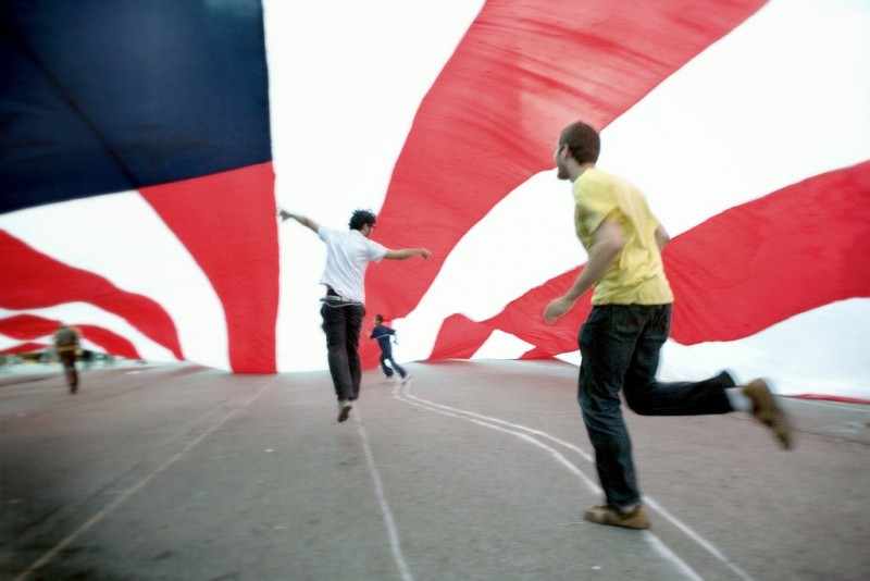 At a First Amendment protest held at Union Square in New York City on April 1, 2008, activists run along the pavement underneath a giant US flag so big it blots out the sky. (Flickr / Luke Redmond)