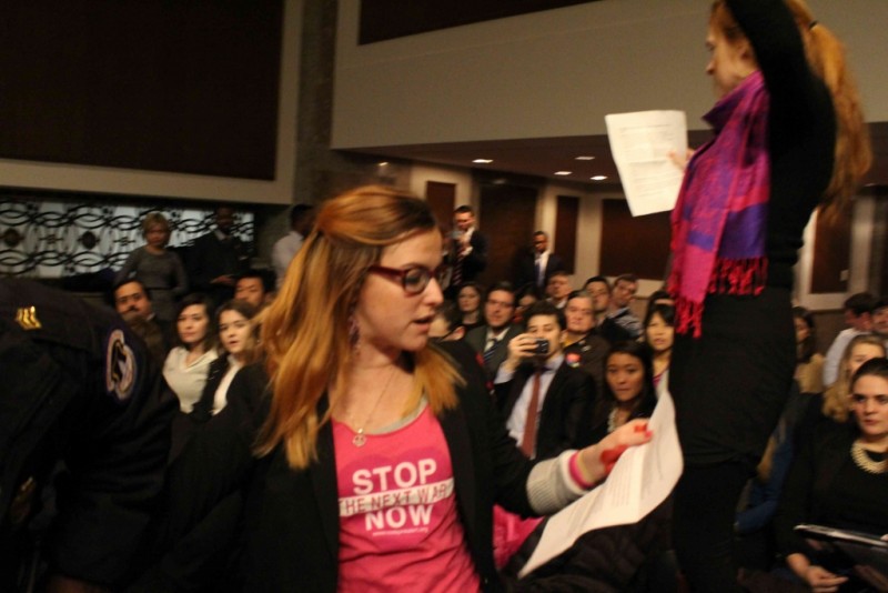A codepink activist reads a prepared speech as police lead her out.
