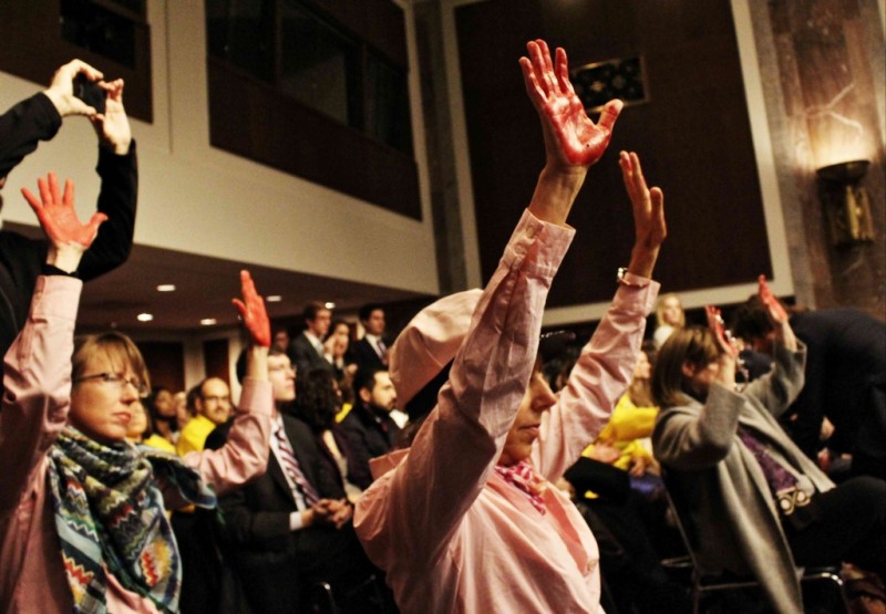 Activists holding up their bloody red hands in the audience.