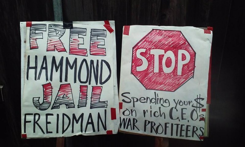 Two picket signs prepared for George Friedmain's book signing in San Francisco. One reads, "Free Hammond, Jail Friedman." Another: "STOP Spending Your $ On Rich CEOs an War Profiteers." (Photo: Ronin)