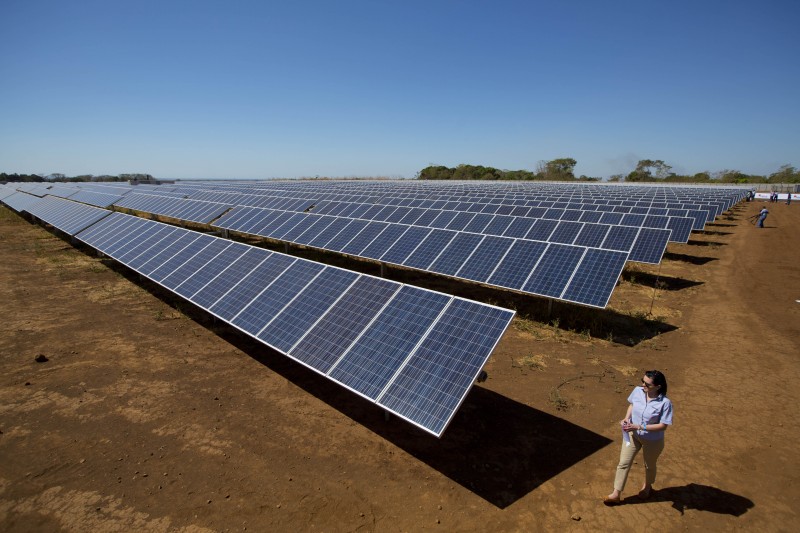 A worker walks alongside rows of solar panels at the Horus photovoltaic power station in Chiquimulilla, south of Guatemala City, Tuesday, Feb. 3, 2015. Thousands of photovoltaic solar panels were installed at the new plant and will have a useful life of 25 years according to the Onyx Group, owners and builders of the power station. (AP Photo/Moises Castillo)