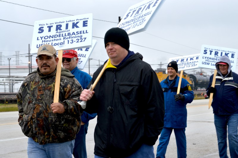 Workers carry picket signs outside the LyondellBasell refinery in Texas' Gulf Coast. The United Steelworkers is leading a historic strike for better working conditions and improved safety at oil refineries and plants throughout the region. (Jane Nguyen)