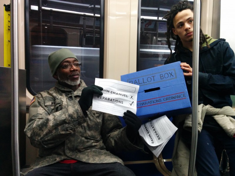 An activist and a commuter pose for the camera with the Reparations Ballot Box and mock ballot in a Chicago train on February 21, 2015. Activists hope a reparations ordinance would help end a pattern of police violence in the city. (Kelly Hayes)