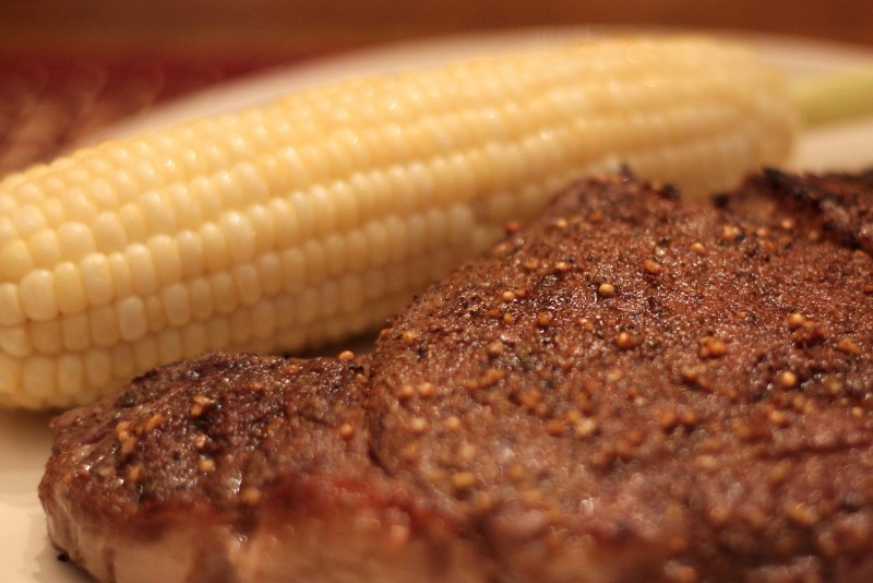 A close-up photo of a steak dinner, with an ear of corn as a side dish. Is meat consumption at current levels a sustainable practice for the planet? (Flickr / Engledow Jenni)