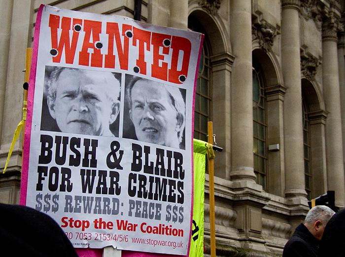 A protester holds up a sign created by Stop The War Coalition, depicting George W. Bush and Tony Blair as war criminals on a Wanted poster. Should the left have placed more blame on Blair for the war? (Flickr / Chris Beckett)