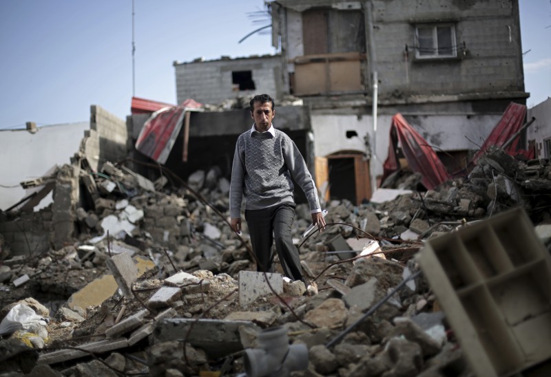 In this Monday, Nov. 17, 2014 photo, Mahmoud Abu Amer, 37, walks amid the ruins of an apartment building where 16 relatives were killed by an Israeli airstrike on July 29, while visiting the site with an Associated Press photographer to make his portrait, in Khan Younis, Gaza. The building was one of scores targeted by Israel in its war last summer with the Islamic militant Hamas. The Western media and politicians allow Israel to make excuses for its war crimes and human rights violations. (AP Photo/Adel Hana)