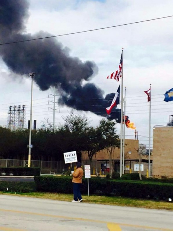 A worker from the USW Strike pickets in front of the LyondellBassell refinery as dark smoke rises, the result of a "flare." Workers say the Emergency Notification System, meant to warn against these incidents, has been deactivated because of their strike. (Photo by Striking USW Worker)