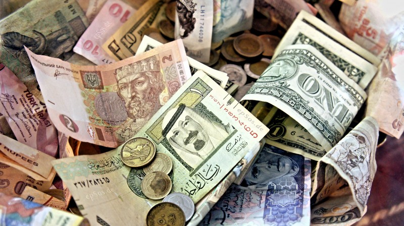 A collection of paper money and coinage from around the world mixed together. Money, and more specifically, the profit motive, have put human life dangerously out of balance on earth. (Flickr / epsos.de)