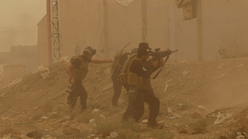 In this May 14, 2015  photo, security forces defend their headquarters against attacks by Islamic State extremists during sand storm in the eastern part of Ramadi, the capital of Anbar province, 115 kilometers (70 miles) west of Baghdad, Iraq. A new government intelligence briefing, released via FOIA request, reveals how the US government predicted the fall of Ramadi to ISIS, and even supported ISIS to help destabilize Syria. (AP Photo, File)