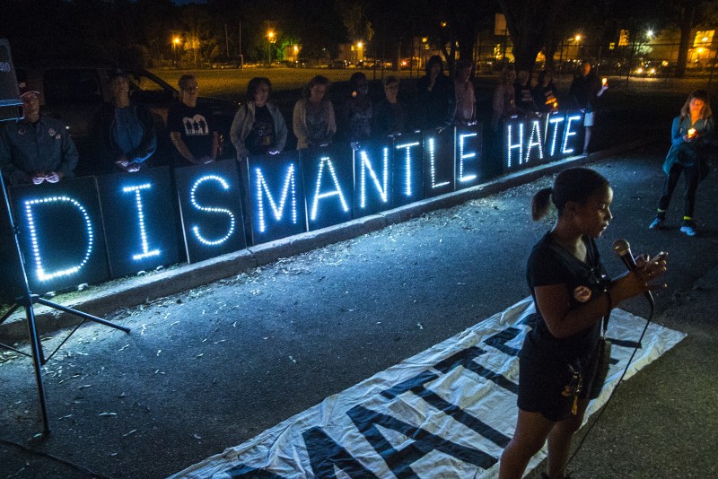 Lighted signs spell out "DISMANTLE HATE" at a rally for the Charleston Shooting held on June 19, 2015 in Madison, Wisconsin. The horrible tragedy in South Carolina which took 9 lives revealed as much about American values as it did about the shooter himself. (Flickr / Light Brigading)