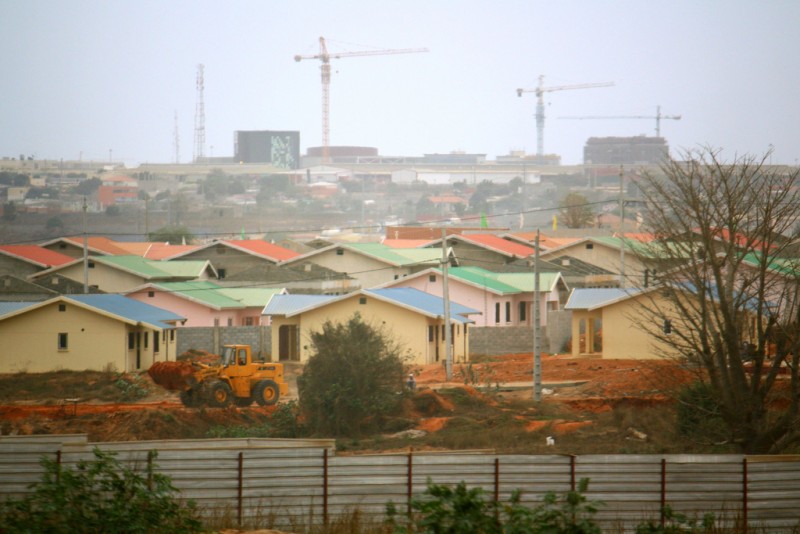 Tall cranes hang over the skyline of Luana, Angola in the background, as a bulldozer moves dirt in a new housing development in the foreground, photographed on September 15, 2010. Rapid growth and extreme poverty in the Angolan capital are bringing new attention to the horrors of global inequality and poverty. (Flickr / Stephen Martin)
