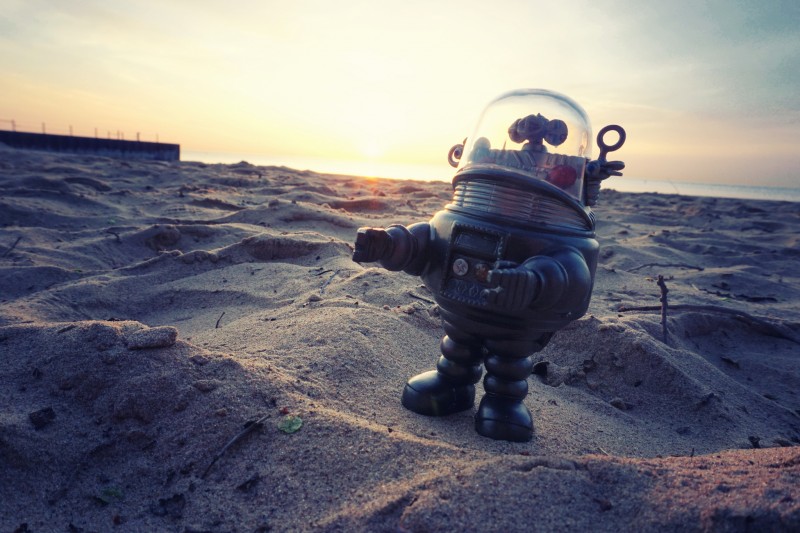 File: A Robbie the Robot toy stands among sand dunes. As automation becomes increasingly commonplace in human lives, it highlights the need for a guaranteed basic income to solve the growing problem of inequality. (Flickr / Dave Mathis)
