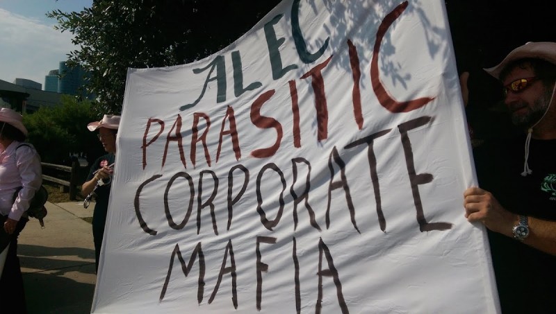 Activists protesting an American Legislative Exchange Council meeting hold a banner reading "ALEC: Parasitic Corporate Mafia" in Dallas, Texas on July 30, 2014. (MintPress News / Kit O'Connell)