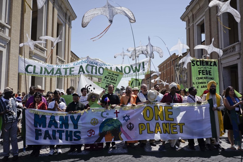People hold banners reading ' Climate action Now ' and ' Many Faiths, One Planet ' in St. Peter's Square, at the Vatican, Sunday, June 28, 2015. Greeting people Sunday from his studio window, Francis praised a few hundred people who marched to St. Peter's Square under the banner "one Earth, one family." Marchers included Christians, Muslims, Jews, Hindus and others. Their route began near the French embassy to remind people of a climate change conference in Paris later this year. (AP Photo/Andrew Medichini)