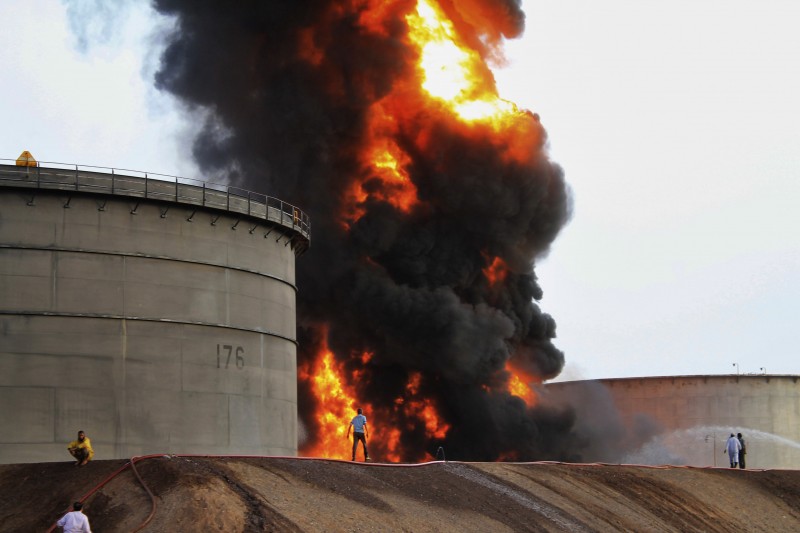 Firefighters work at the storage tanks of an oil refinery following rocket attacks by Shiite rebels, known as Houthis, in the port city of Aden, Yemen, on Tuesday, July 14, 2015. Yemeni forces battling the Shiite rebels in the country's south said they took control on Tuesday of the airport in the strategic port city of Aden, driving the rebels there into the part of the city jutting out into the sea. (AP Photo/Abo Muhammed)