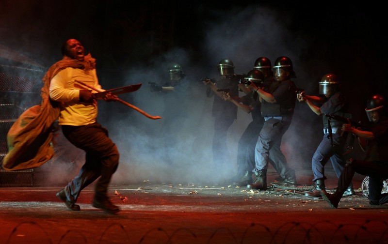 In this photo taken Thursday, Aug. 13, 2015 actors, re-enact the scene when police, right, open fire on striking platinum mineworkers, in the musical "Marikana" in Pretoria, South Africa. South Africans sing and dance when they mourn, which is why a musical is a fitting way to commemorate the police shootings of striking miners three years ago, says the lead actor of Marikana - The Musical. On Aug. 16 2012, a weekslong labor dispute reached a bloody climax as police opened fire and killed 34 miners in Marikana, a mining town in the North West province. Mavuso Magabane plays the leader of the strike who was killed in the shootings that were the largest loss of life in a police operation since South Africa achieved majority rule in 1994. (AP Photo/Themba Hadebe)