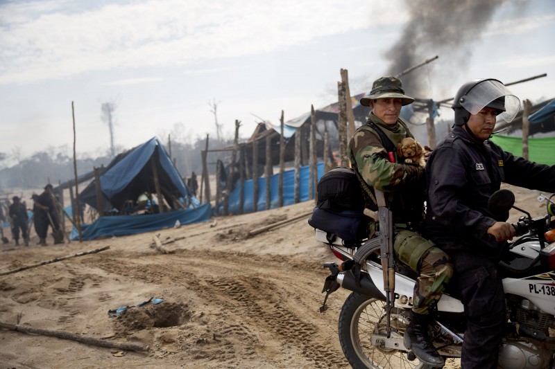 A police officer cradles a dog he picked from a mining camp during an operation to eradicate illegal mining in the area known as La Pampa, in Peru's Madre de Dios region, Wednesday, Aug. 12, 2015. This past week, Peruvian security forces cleared out nearly six square miles in a crater-pocked jungle zone where some 10,000 people lived, blowing up 154 gasoline motors used to extract gold from the sandy soil. (AP Photo/Rodrigo Abd)