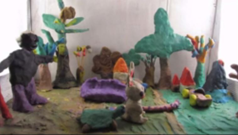 An image from A colorful tableau made of clay, created "The Dream of the Magical Sofa," a claymation film created by Sudanese asylum seekers' children. At the center of a clay tableau sits a purple couch. (ProMosaik)