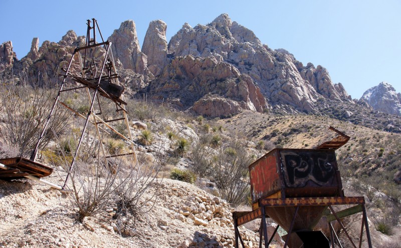Abandoned equipment at the Hayner Ruby Mine in Boyd, New Mexico. The A frame on the left was used to lift mine cars from a vertical shaft, whose contents would be emptied into the hopper on the right. The Organ Mountains' Rabbit Ears are nearby. (Flickr / Samat Jain)