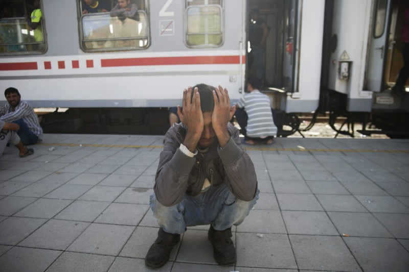 A refugee covers his face as he squats down at the railway station of Beli Manastir, Croatia, Friday, Sept. 18, 2015. Croatia declared it was overwhelmed and began busing migrants in convoys back to Hungary and closing its border crossings with Serbia. (Zoltan Balogh/MTI via AP)