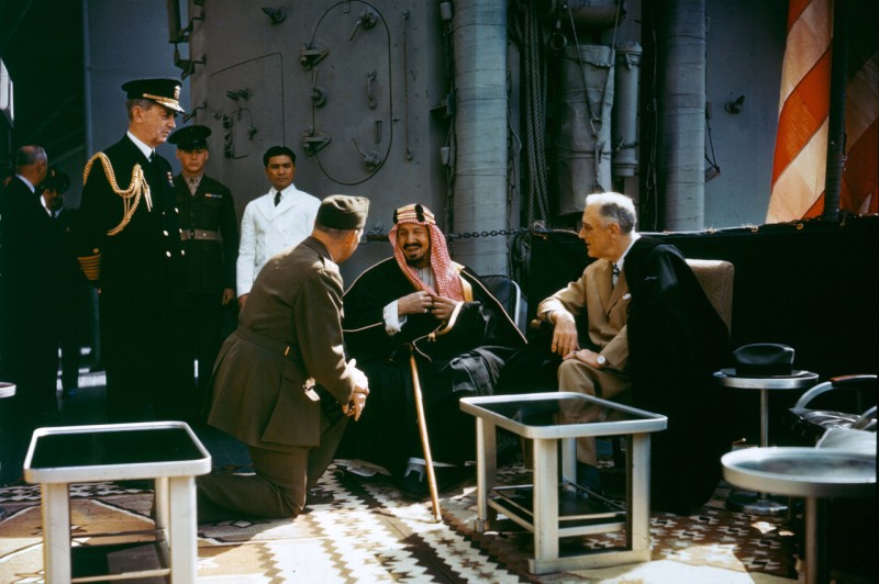 President Franklin Delano Roosevelt Meets with King Ibn Saud, of Saudi Arabia, on board USS Quincy (CA-71) in the Great Bitter Lake, Egypt, on 14 February 1945. The King is speaking to the interpreter, Colonel William A. Eddy, USMC. Fleet Admiral William D. Leahy, USN, the President's Aide and Chief of Staff, is at left. (Wikimedia Commons / US Government)