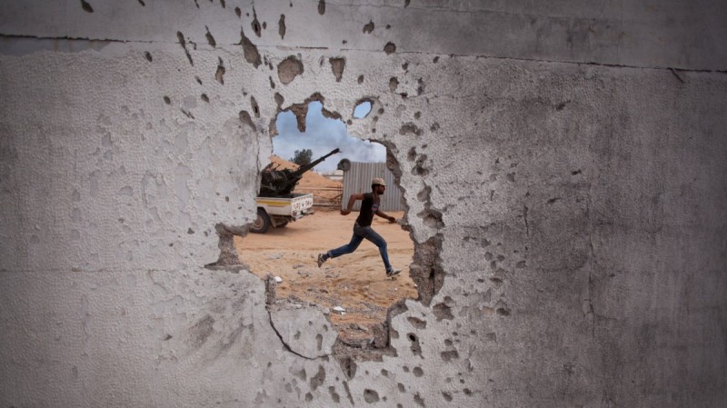 A Libyan revolutionary fighter runs for cover while attacking pro-Gadhafi forces in Sirte, Libya, Friday, Oct. 7, 2011. (AP Photo/Manu Brabo)