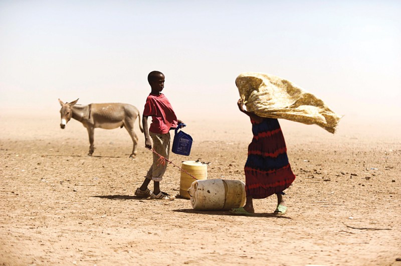 A Kenyan woman and boy struggle with the dusty wind while looking for water on July 16, 2011. (Flickr / Kenya Red Cross Society / Jervis Sundays)