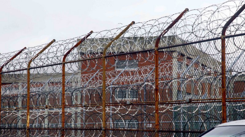 In this March 16, 2011 file photo, inmate housing on New York's Rikers Island correctional facility can be seen on the other side of a fence topped with razor wire. (AP Photo/Bebeto Matthews, File)