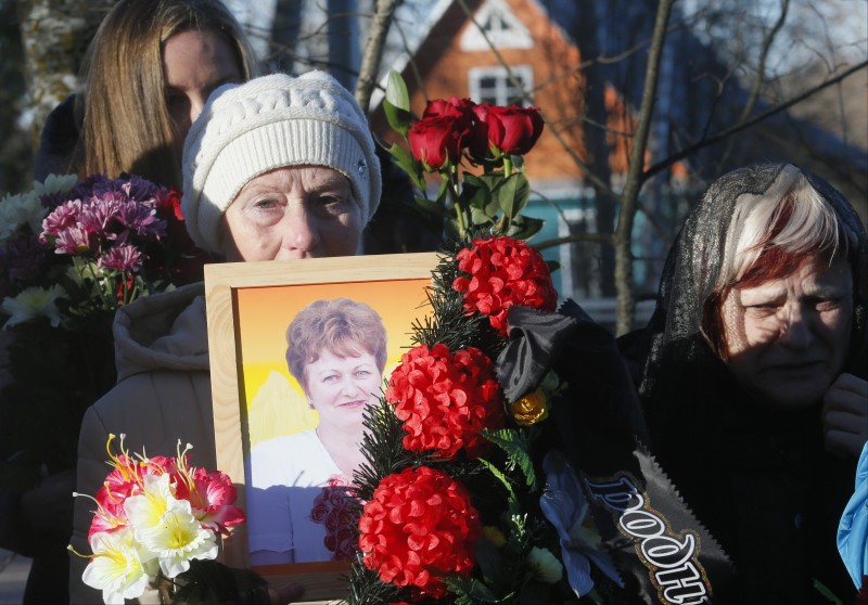 A woman holds a portrait of Nina Lushchenko, one of the victims of a plane crash, during her funeral at a cemetery in the village of Sitnya, 80 km (about 50 miles) of Veliky Novgorod, Russia, Thursday, Nov. 5, 2015. The first victim of Saturday's plane crash in Egypt was laid to rest on Thursday following a funeral service in a medieval church in the north Russian city of Veliky Novgorod. Russia's Airbus 321-200 broke up over the Sinai Peninsula en route from the resort town of Sharm el-Sheikh to St. Petersburg, killing all 224 on board. (AP Photo/Dmitry Lovetsky)
