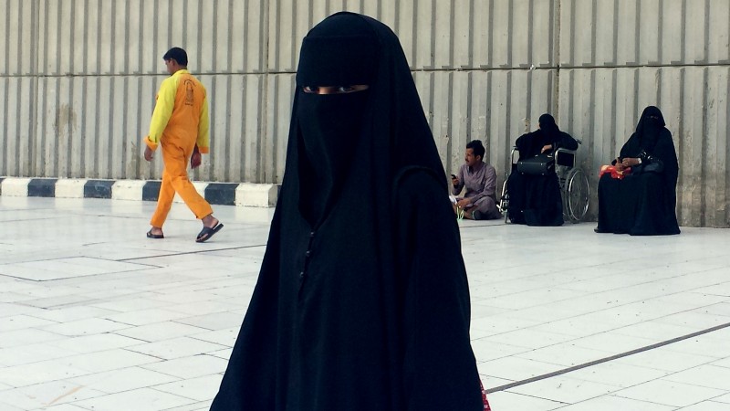 A veiled woman walking in Mecca, Saudi Arabia, where society is governed by a mix of ancient customs and conservative interpretations of Islam. Most women cover their face and by law must wear long flowing black abayas in public. (AP Photo/Aya Batrawy)