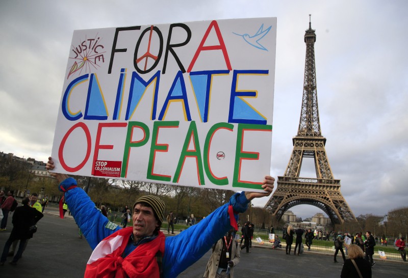 An activist hold a poster during a demonstration near the Eiffel Tower, in Paris, Saturday, Dec.12, 2015 during the COP21, the United Nations Climate Change Conference. As organizers of the Paris climate talks presented what they hope is a final draft of the accord, protesters from environmental and human rights groups gather to call attention to populations threatened by rising seas and increasing droughts and floods. (AP Photo/Thibault Camus)