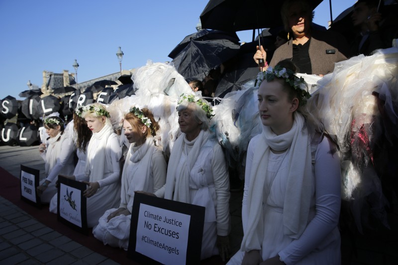 Activists stage a protest outside the Louvre pyramid, calling on the museum to cancel its contracts with French oil giant Total and Italian oil company Eni, in Paris, Wednesday, Dec. 9, 2015 . The protest is one of many activist actions linked to the COP21, the United Nations Climate Change Conference. (AP Photo/Christophe Ena)