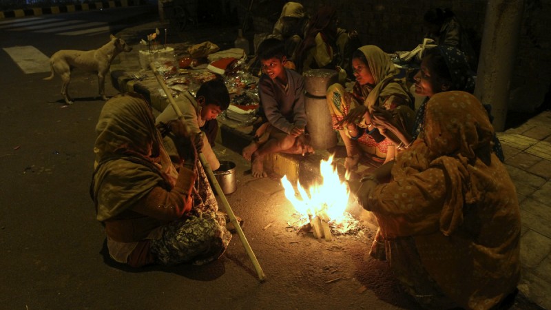 An Indian family living on a roadside keeps themselves warm by sitting around a bonfire in Ahmedabad, India, Friday, 26, 2014. Cold wave conditions continues unabated in the northern region with fog enveloping most areas and affecting transport services. (Photo: Ajit Solanki/AP)