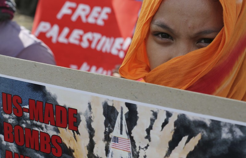 A Filipino activist holds a slogan during a rally in observance of the International Day of Solidarity with the Palestinian People in front of the U.S. Embassy in Manila, Philippines Sunday, Nov. 29, 2015. (AP Photo/Aaron Favila)