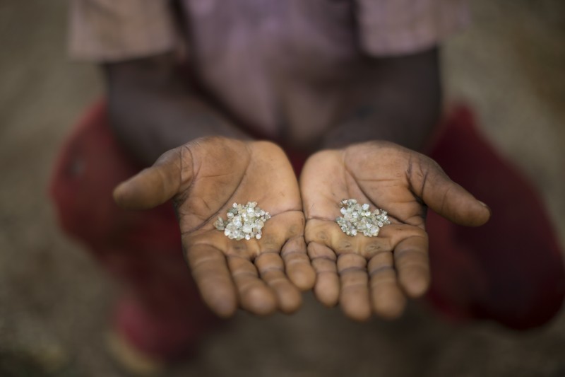 In this Nov. 19, 2015 photo, an artisanal miner shows the diamonds he and his group found in an abandoned mine in Areinha, Minas Gerais state, Brazil. The area has been explored for the precious stone since the time of slavery, and up to a couple of years ago, multinational mining companies extracted the stone without care for the land or the Jequitinhonha river that crosses the region. (AP Photo/Felipe Dana)